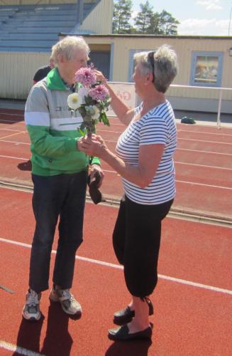 Berith Karlsson överlämnar en blomsterkvast till Carl-Erik